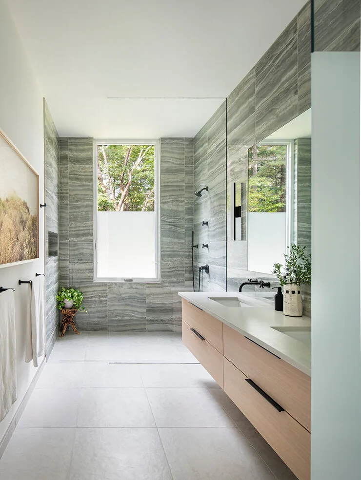 The Noanet Woods Modern bathroom features gray marble tile walls, a floating double vanity, and a walk-in shower with black fixtures.