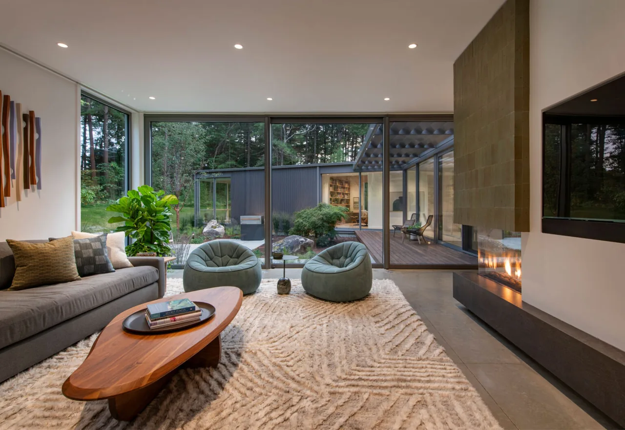 Living room in Noanet Woods Modern features floor-to-ceiling glazing and a corner fireplace with textured wall.