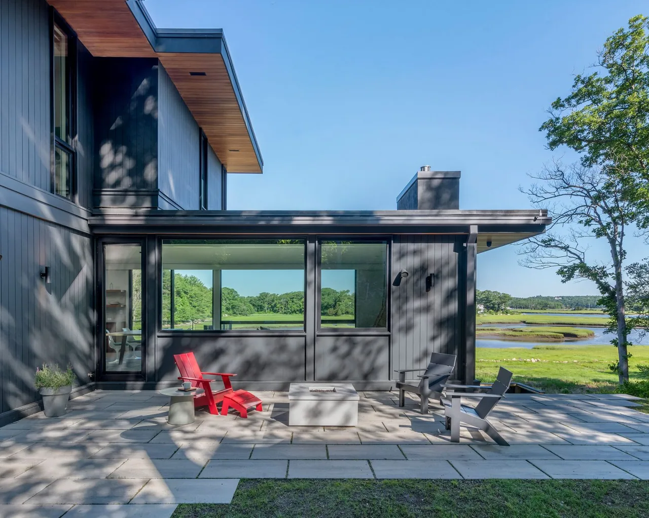 Patio with dark vertical siding and gray stone pavers facing a scenic marsh view at Tidal Marsh Overlook.