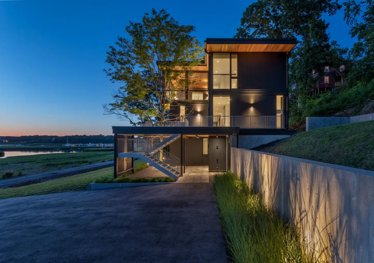 Tidal Marsh Overlook features a modern multi-story design with vertical wood paneling and exterior stairs overlooking a marsh.