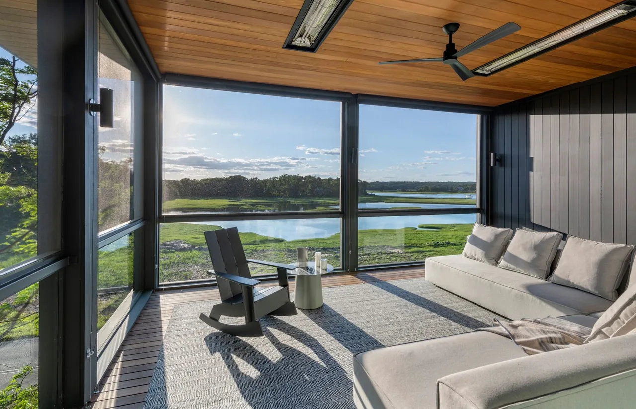 Screened patio at Tidal Marsh Overlook features dark walls and ceiling with ample natural light and a marsh view.