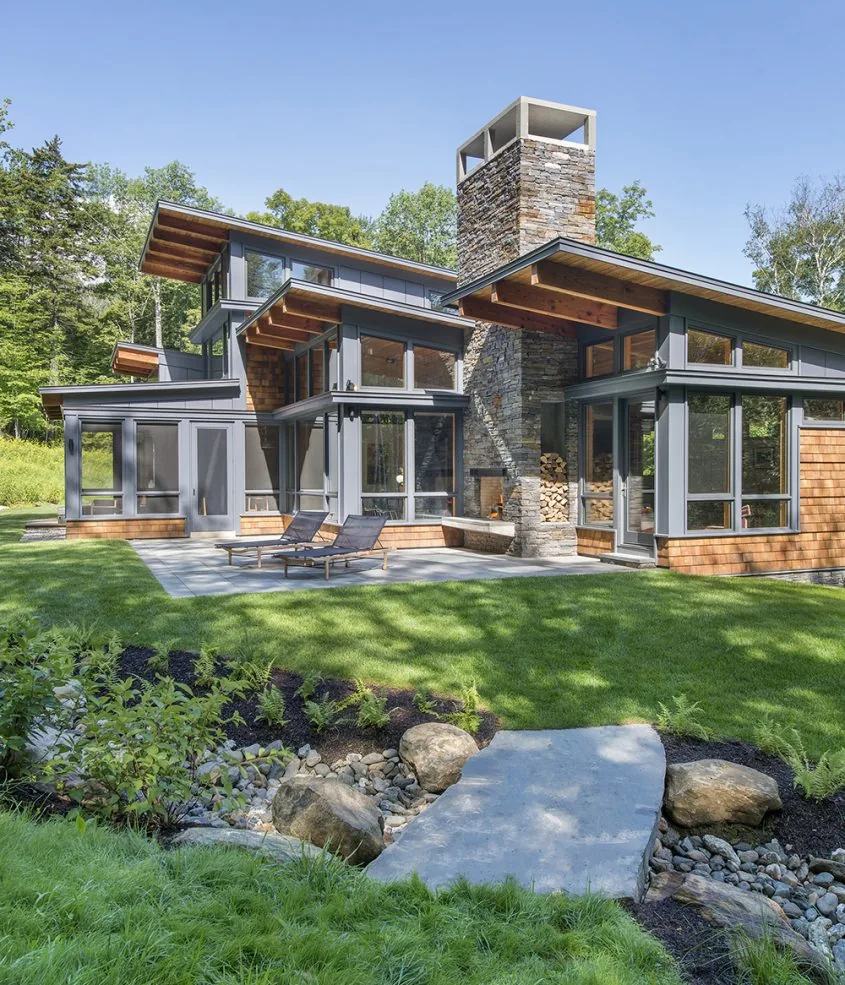 Green Mountain Getaway features a stone chimney and clerestory windows with a landscaped outdoor area.