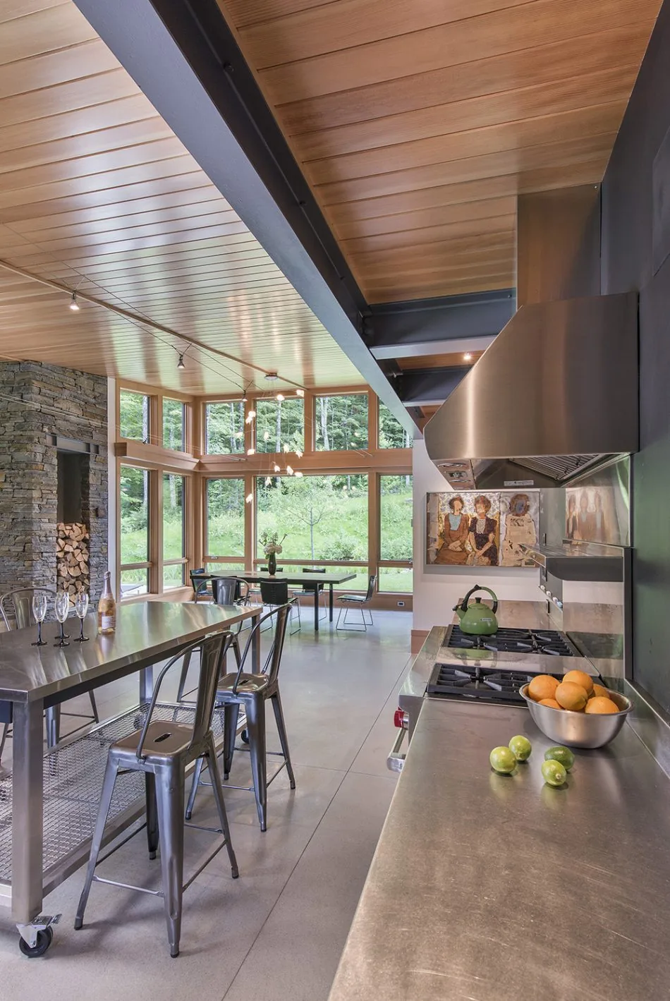 The Green Mountain Getaway kitchen features stainless steel counters and stools, with expansive clerestory windows bringing in natural light.