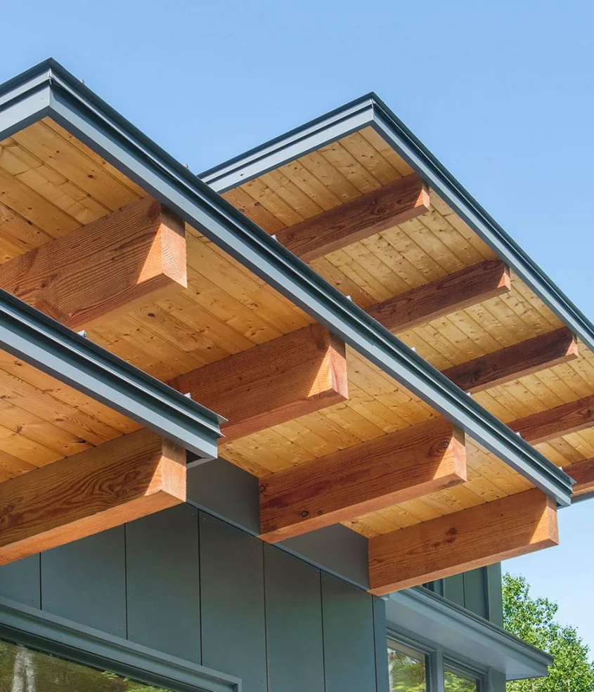 Exposed wooden beams support the roof overhang on the home's exterior, highlighting natural wood elements.