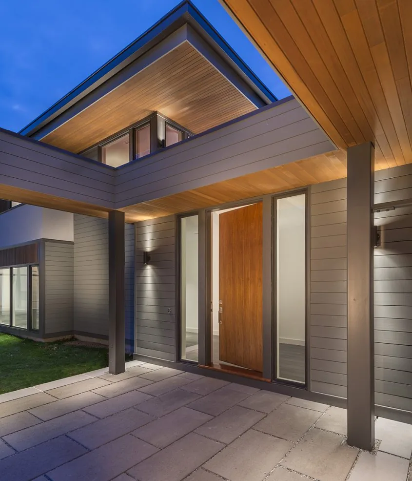 Exterior front porch of the Modern Blueberry Farm project features a wood accent entry door and horizontal siding with integrated lighting.