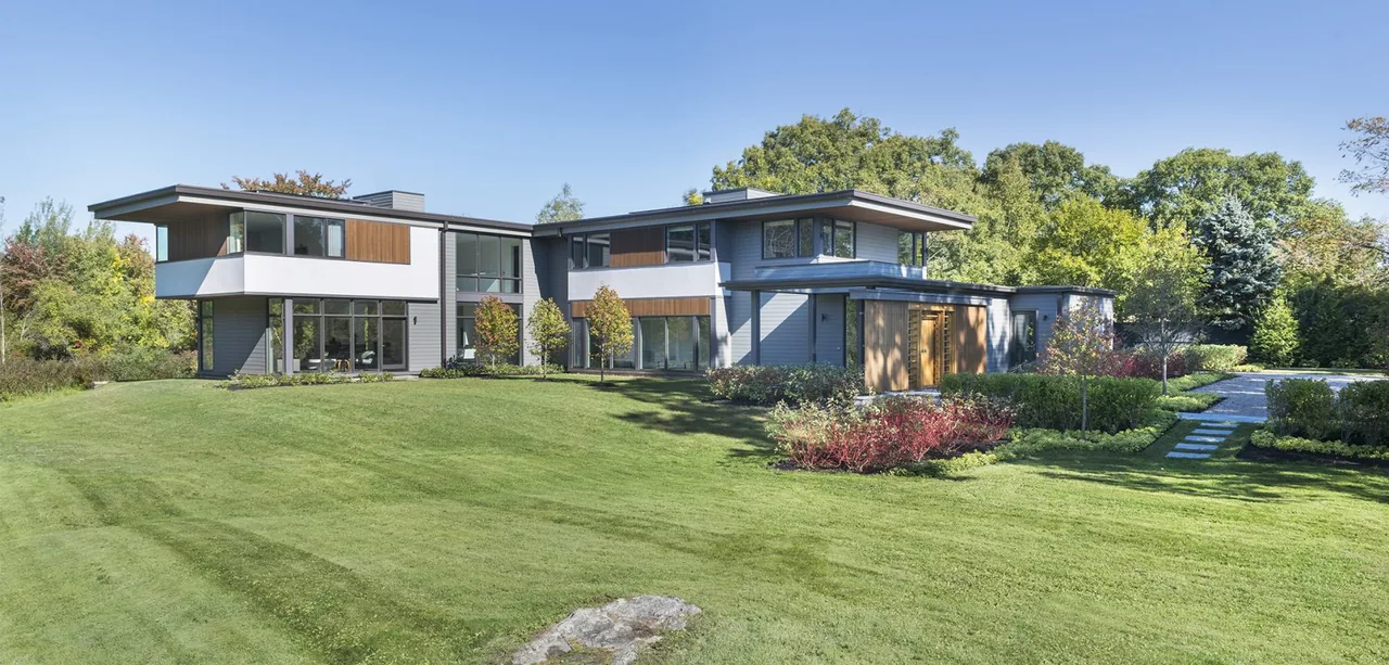 Modern Blueberry Farm features a two-story design with large windows and a mix of wood and gray siding.