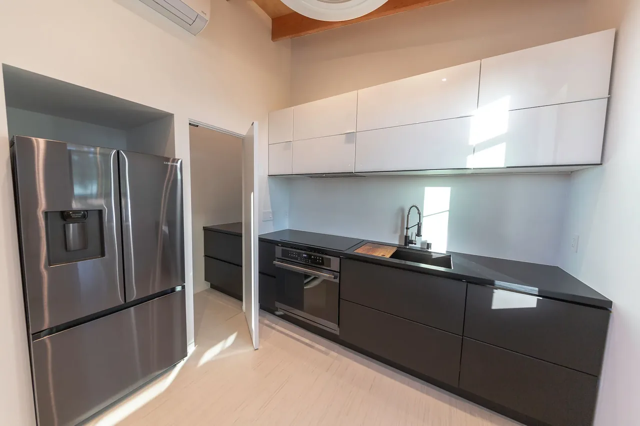 The Prince House ADU features a modern kitchen with black and white cabinetry and stainless steel appliances.