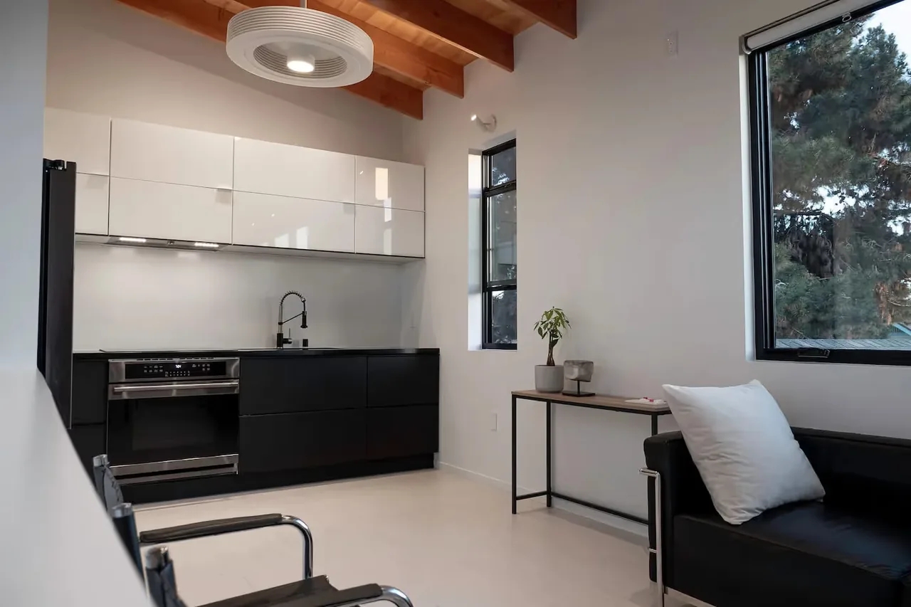 The Prince House ADU kitchen features high contrast cabinetry and exposed wood beam ceiling.