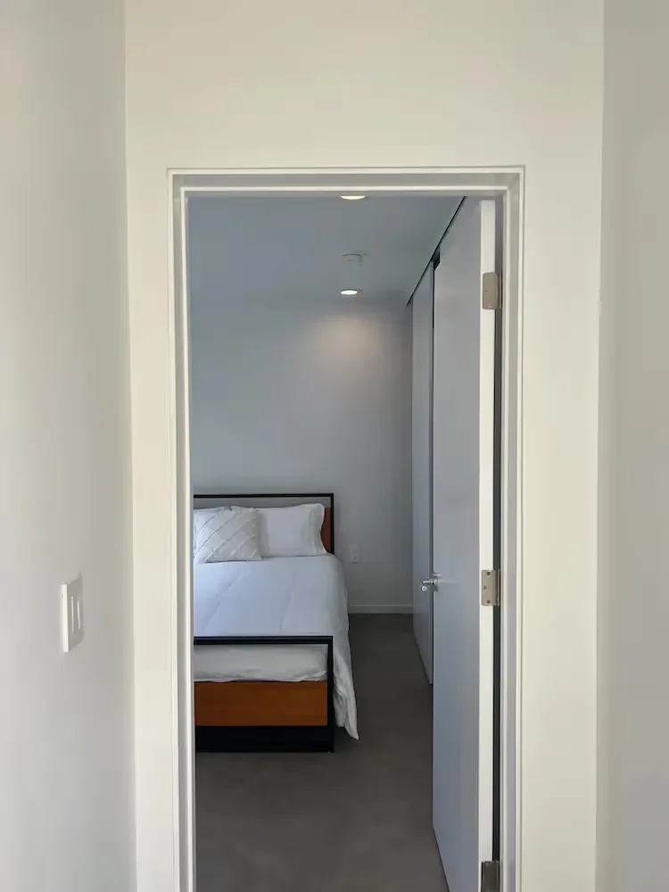 Minimal bedroom in The Prince House ADU with white bedding and a simple black and wood bed frame.