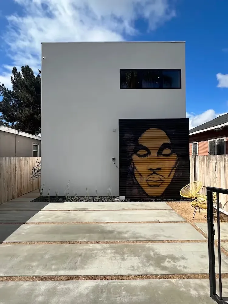 The Prince House ADU by Ten Seventy Architecture features a minimalist facade with a facial mural on the garage door.