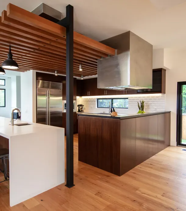 Kitchen interior featuring a wood-slat ceiling structure, stainless steel appliances, and a white island with integrated sink.