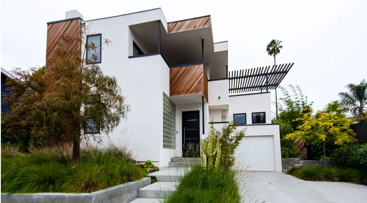 The Edinberg Residence features a modern exterior with white stucco, wood siding, and a metal slat pergola in San Diego.