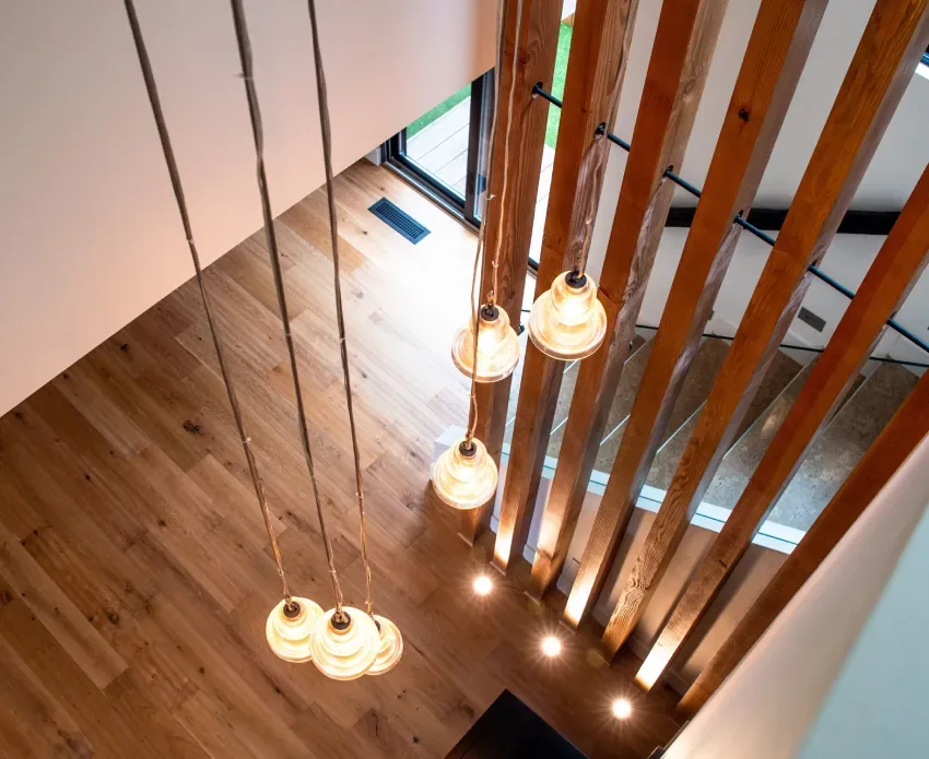 Interior view of a staircase with vertical wood beams and pendant lighting in The Edinberg Residence.