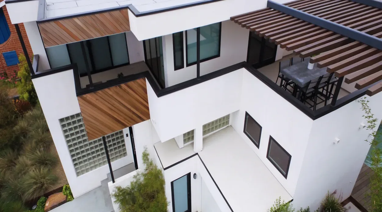 The Edinberg Residence features angular wood siding, black window frames, and a rooftop deck with a metal slat pergola.