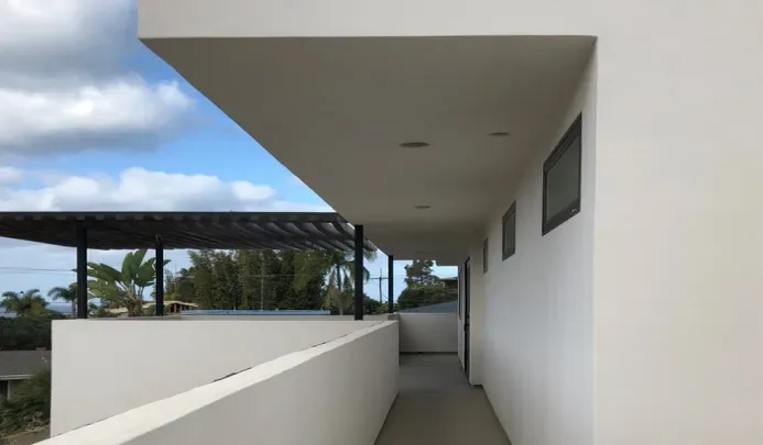 The Edinberg Residence features a clean, white exterior corridor with overhanging eave and small horizontal windows.