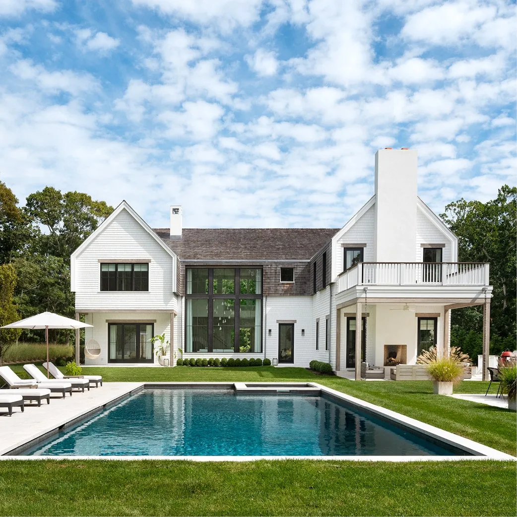 The Amagansett House features a covered patio, balcony, and a pool with lawn seating in the rear exterior view.