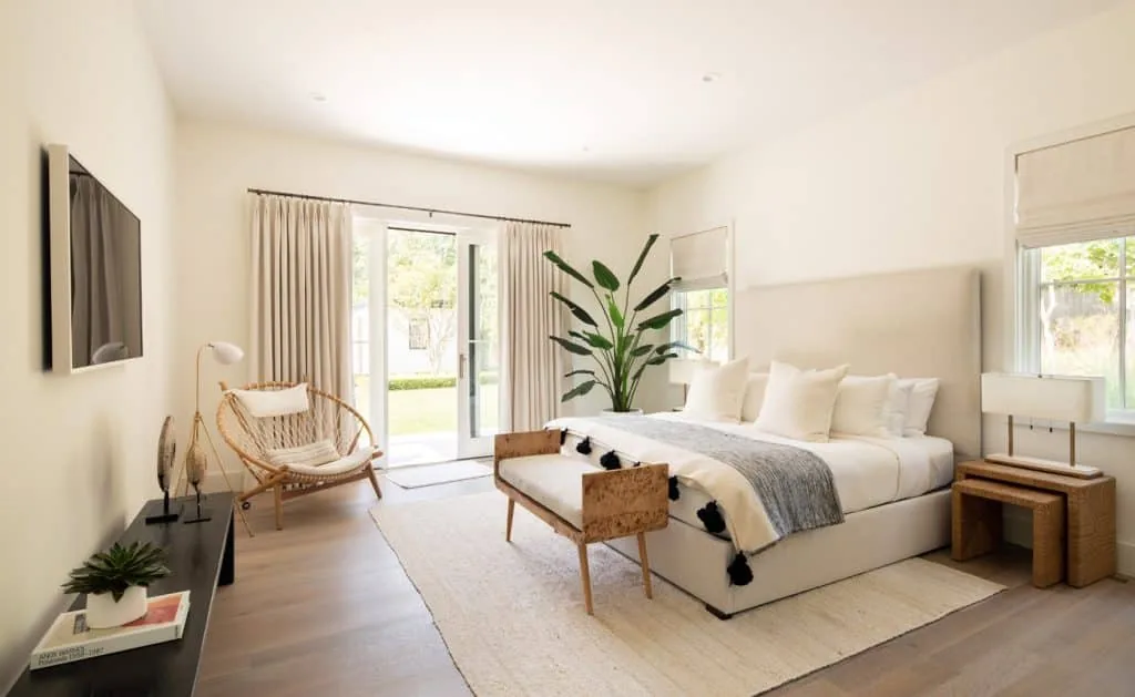 The Amagansett House bedroom features a large bed, glass door to yard, and neutral decor with natural light.