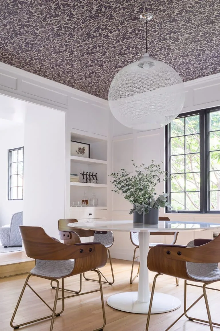 The Newton Tudor dining space features a round white table with wooden chairs and a distinctive patterned ceiling.