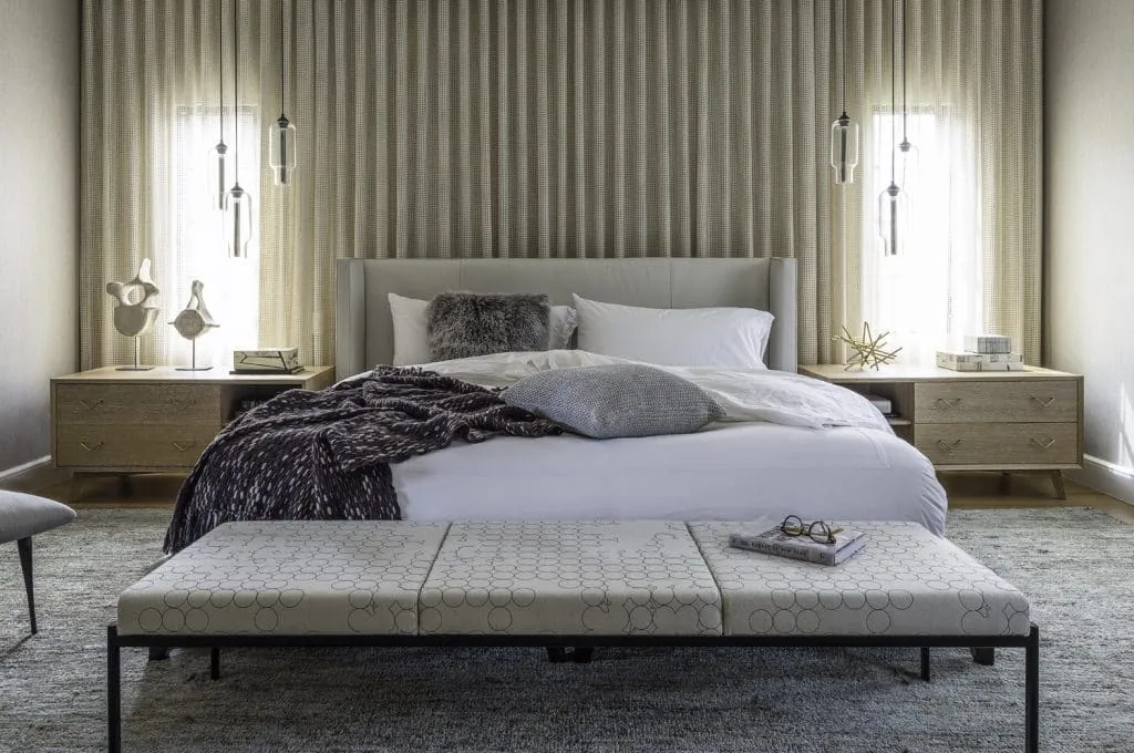 Bedroom with modern upholstered bed, floating wooden nightstands, and pendant lighting in neutral tones.
