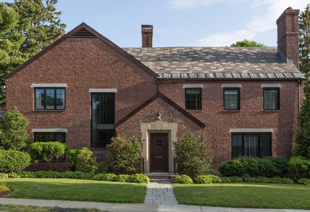 Newton Tudor features a traditional brick exterior with black window frames and a slate gable roof.