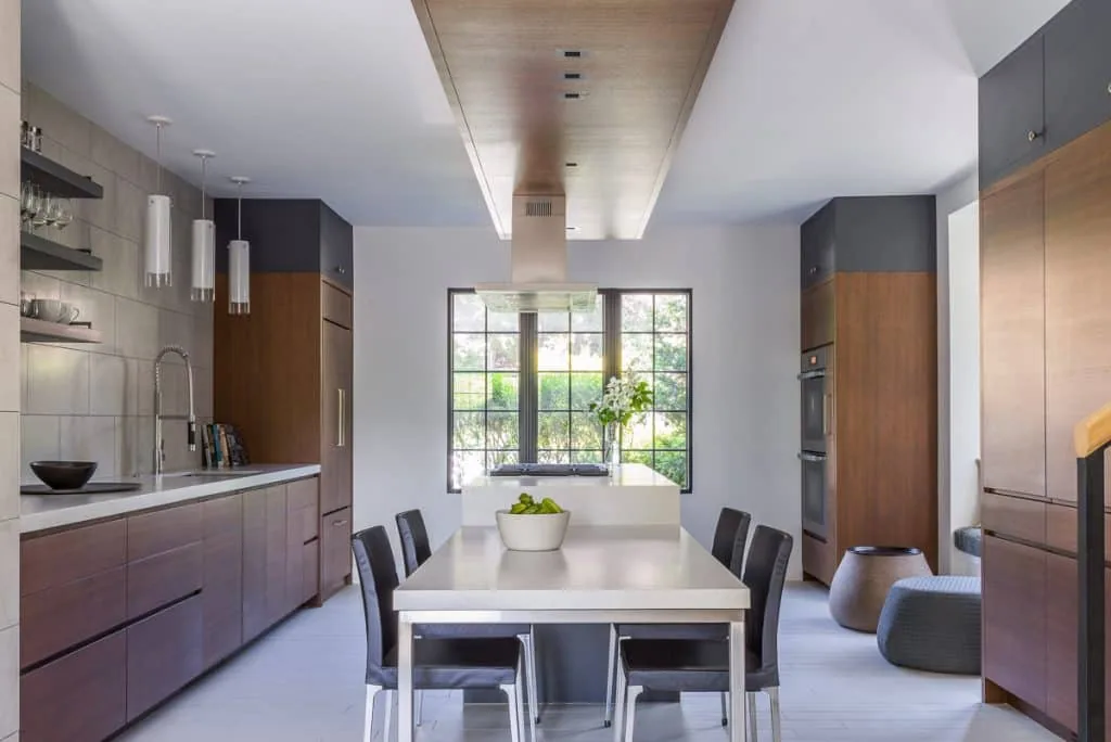Kitchen with dark wood cabinetry, a white island, and a large multi-pane window providing outdoor views.