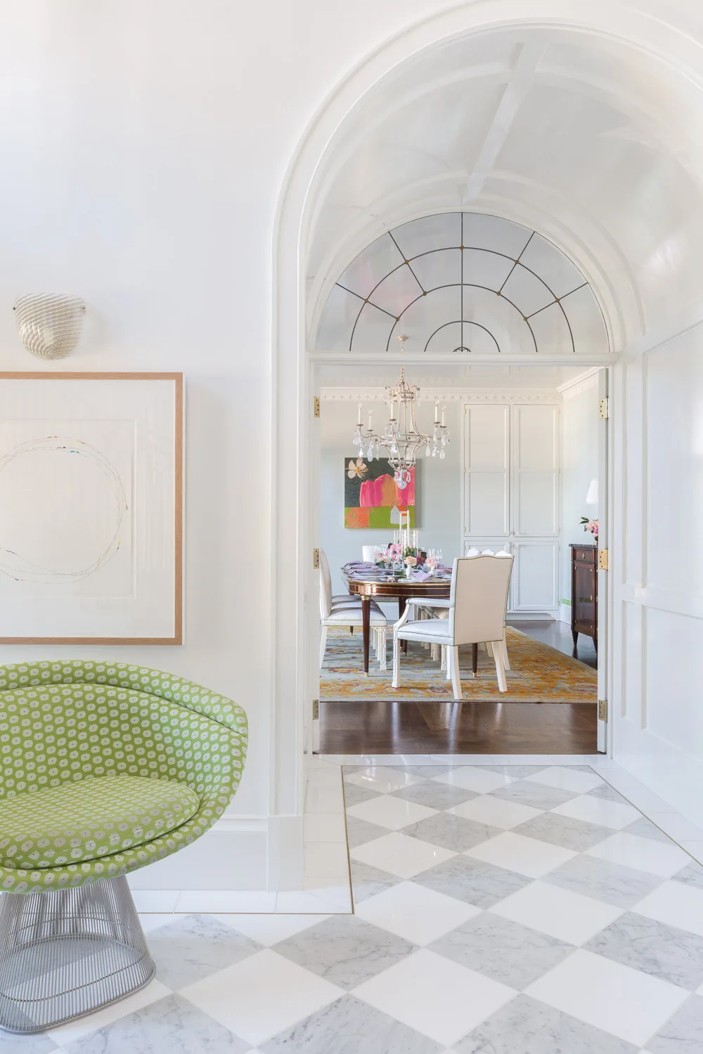 The dining room is visible through a large white arched doorway with patterned marble flooring in the foreground.