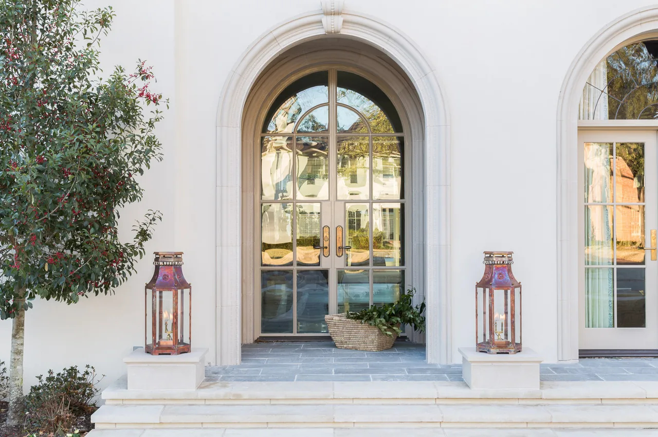 The Belclaire project features an arched front entry with divided lite glass doors and stone steps leading to the porch.