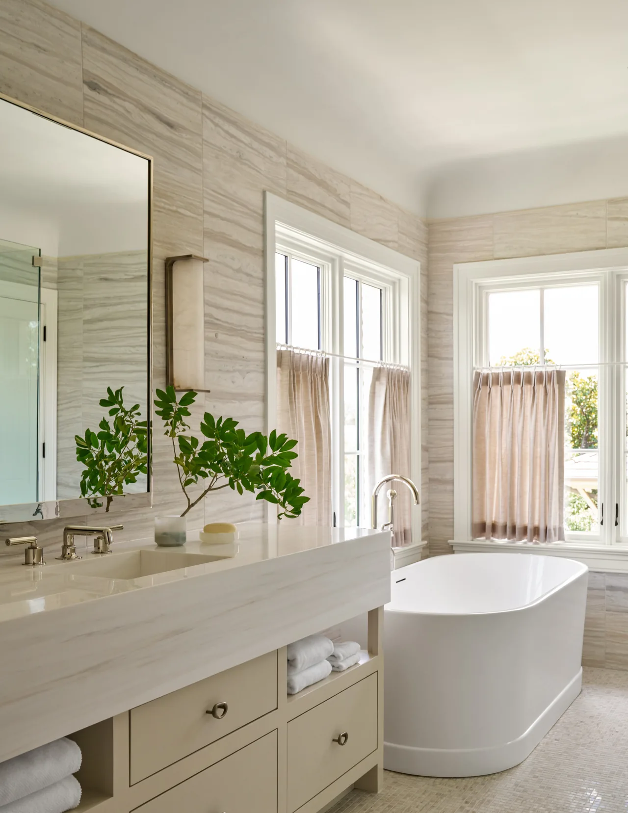 Bathroom features a freestanding tub, beige vanity with metal drawer pulls, and beige roman shades on the windows.