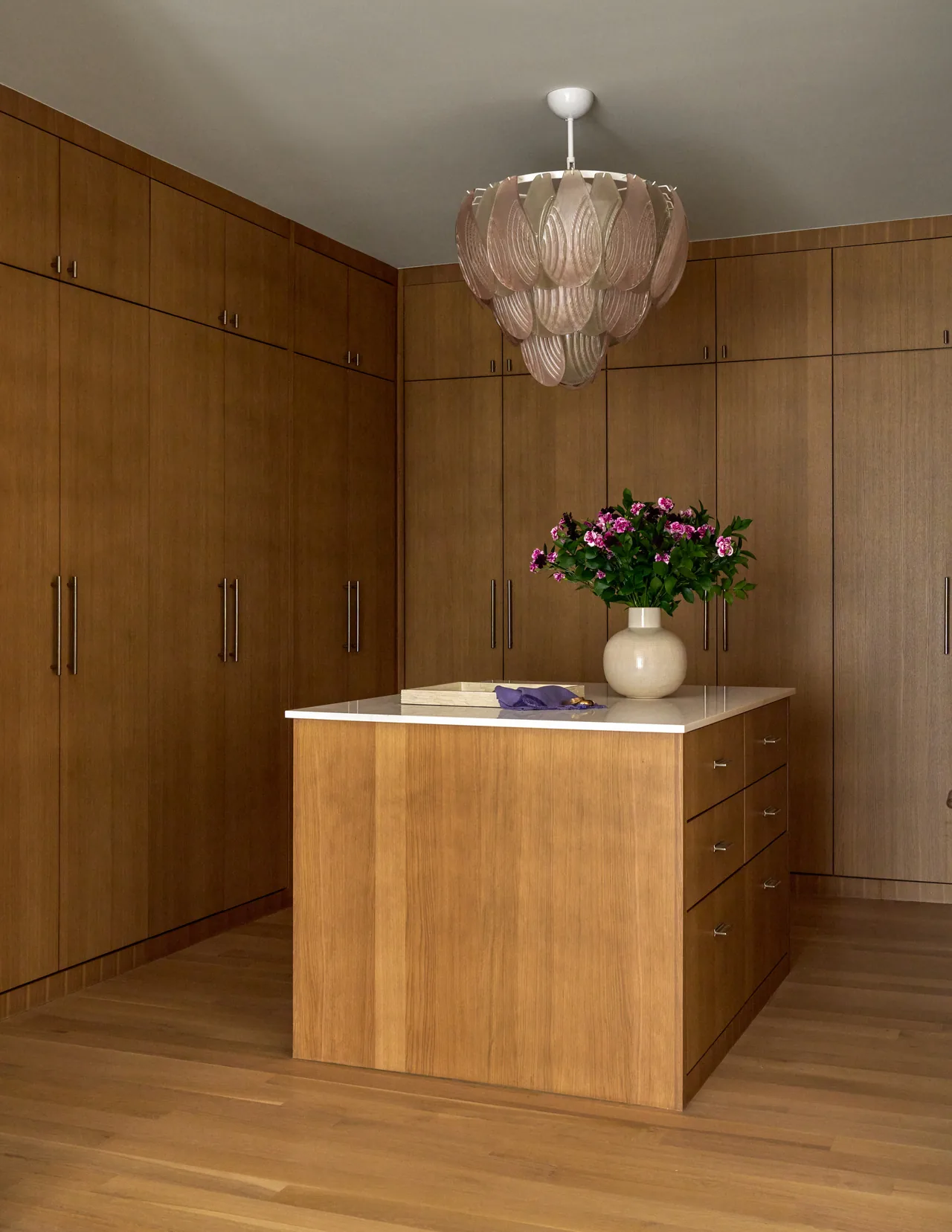 Wood-paneled kitchen with central island and ornamental pendant light above.