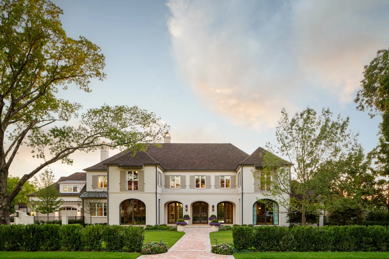 The New Classic house by Blume Architecture features arched openings and a symmetrical facade with beige stucco walls.