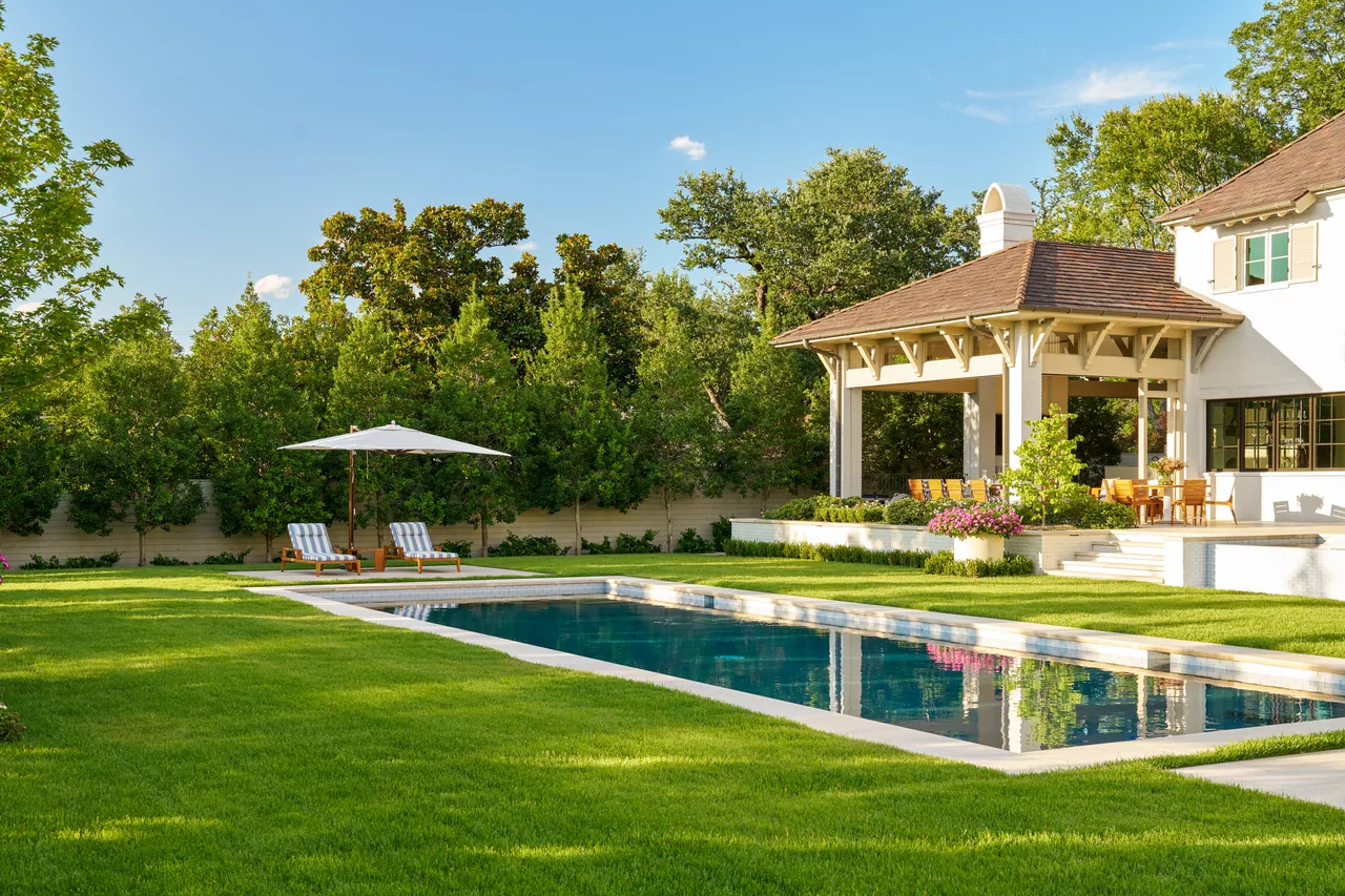New Classic project showing a backyard with a covered patio, dining area, pool, and lounge chairs under an umbrella.