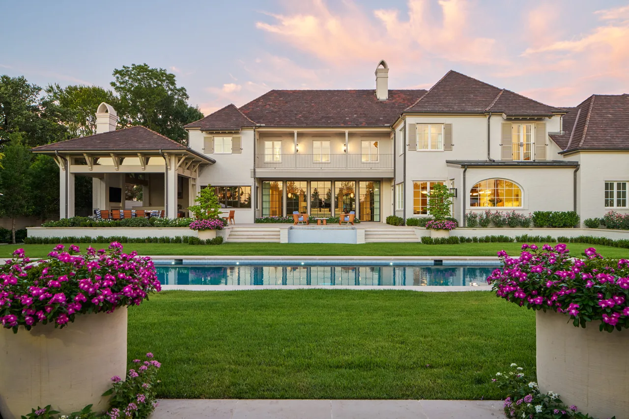 The New Classic project showcases a traditional two-story home with a tiled roof and outdoor living space centered around a rectangular pool.