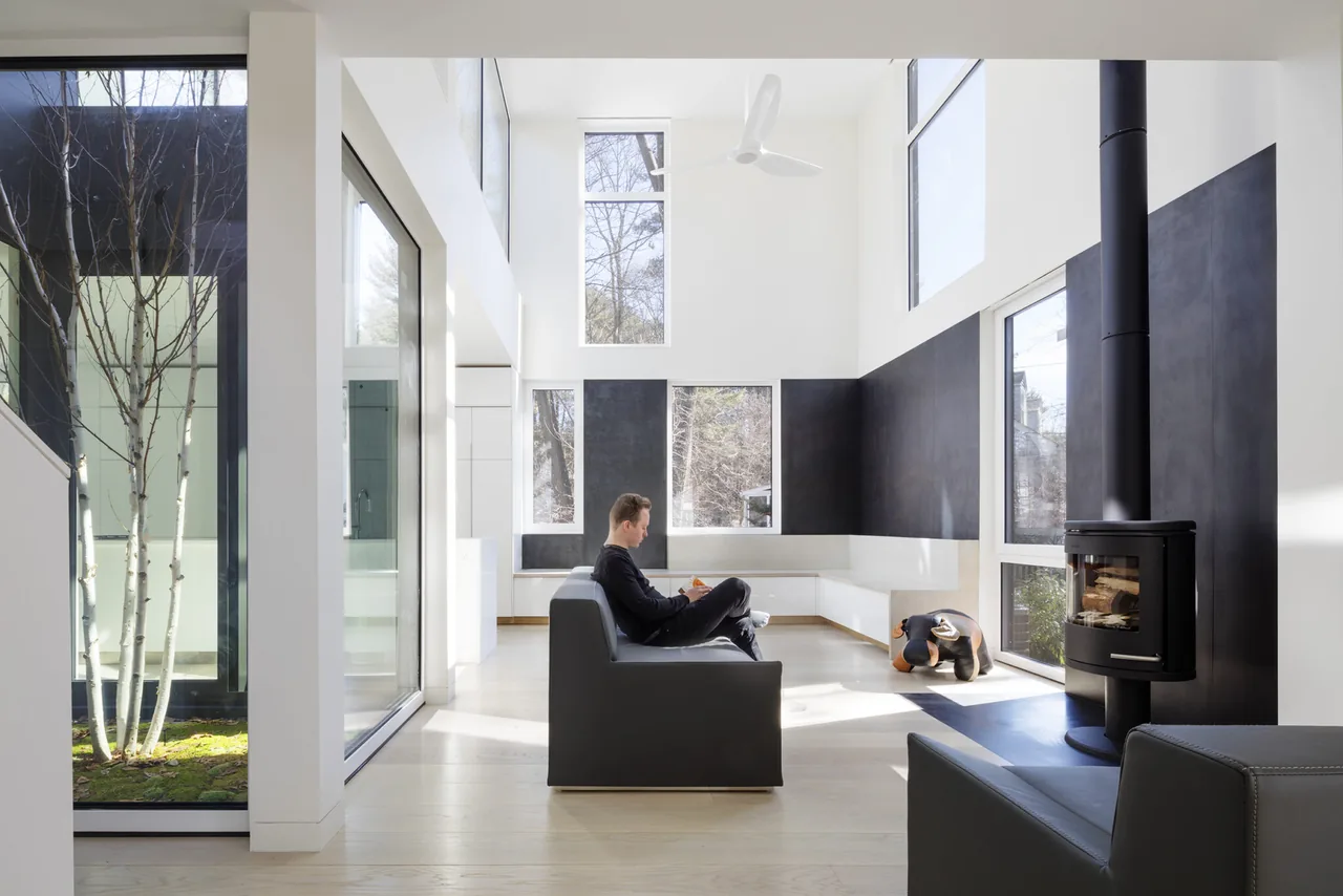 The Grow Box living room features double-height ceilings, floor-to-ceiling glazing, and a black wood stove accent wall.