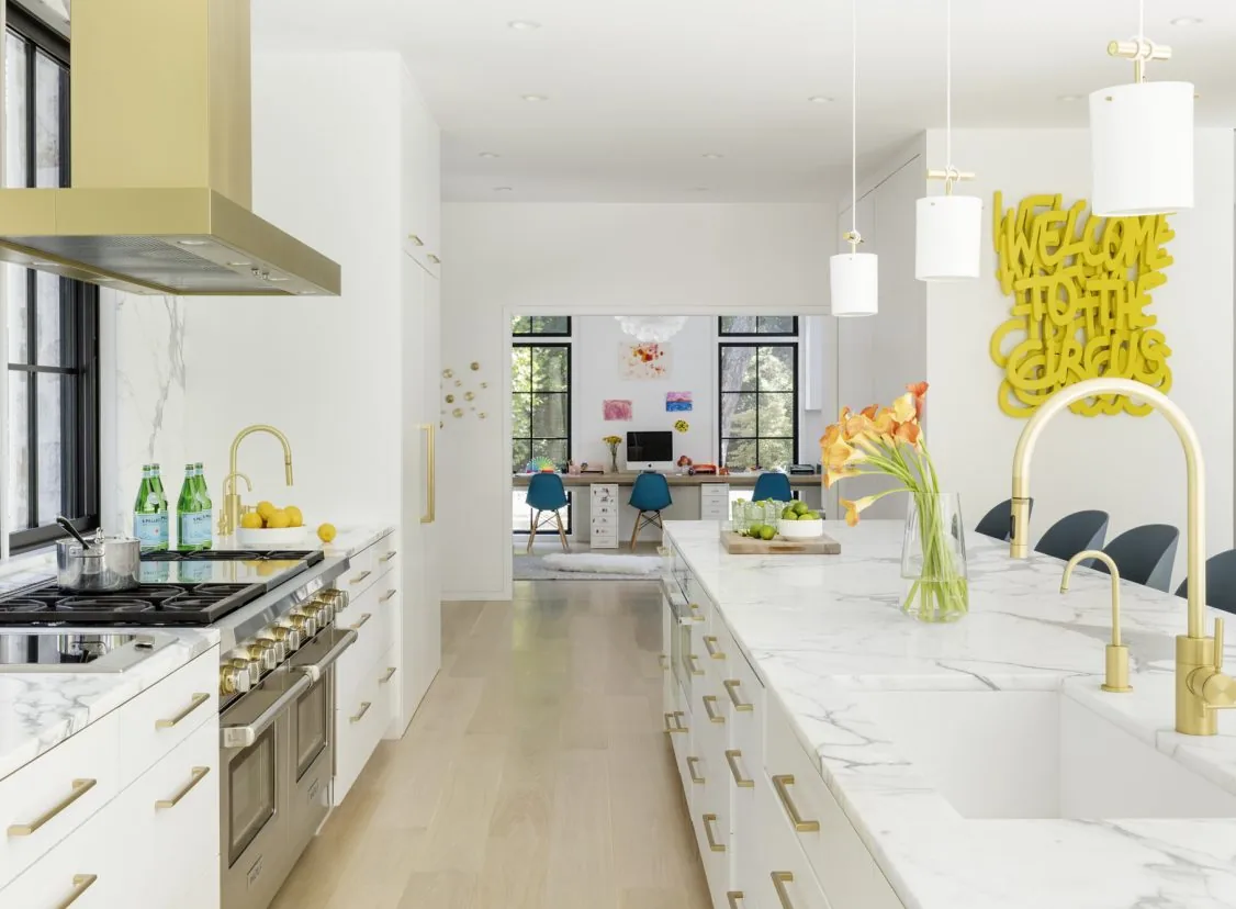 The kitchen features a marble waterfall island, gold hardware, and black window frames, with a study visible beyond the doorway.