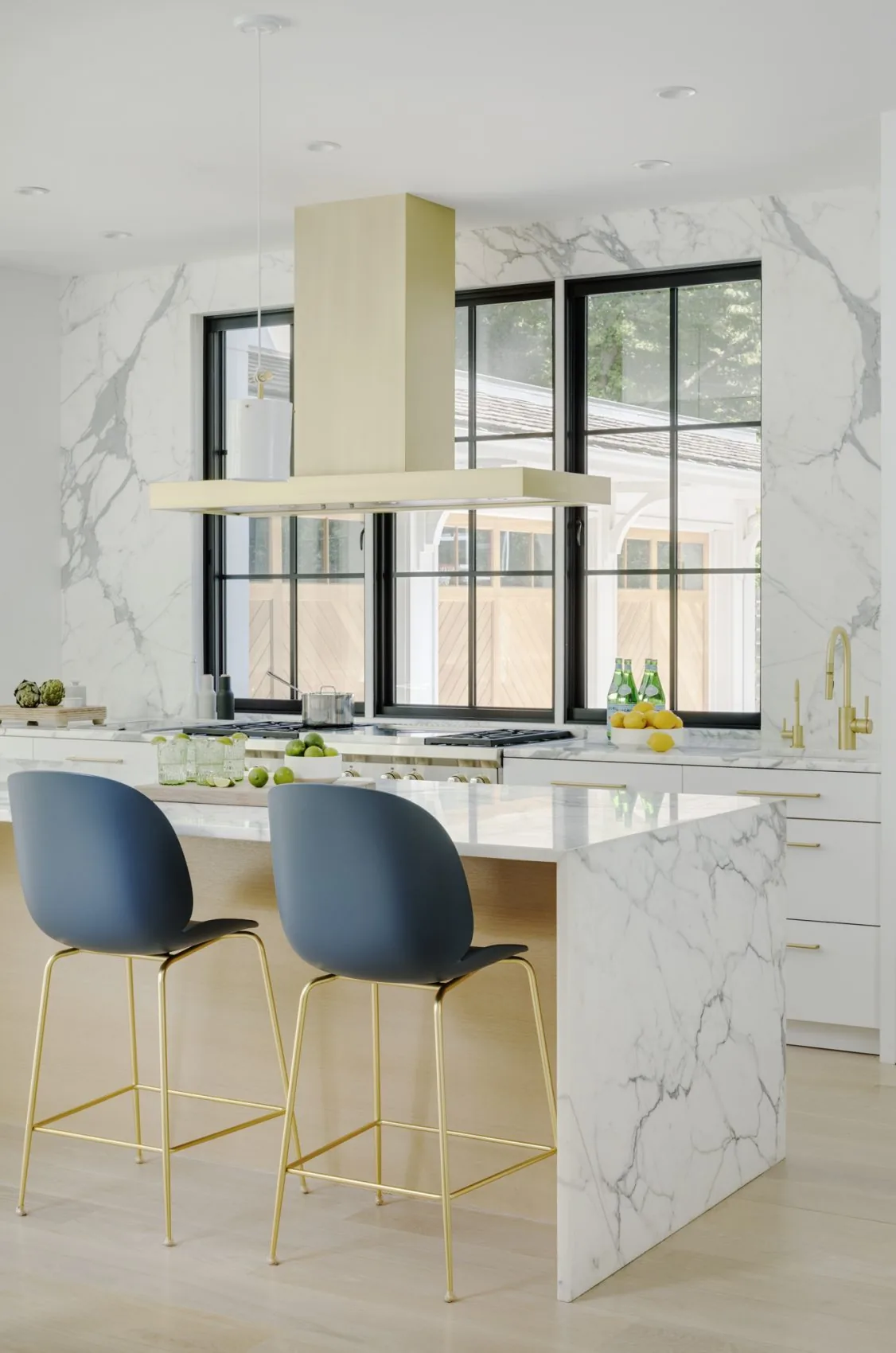 The Birchwood Terrace kitchen features a marble island and backsplash with brass fixtures and modern black window frames.