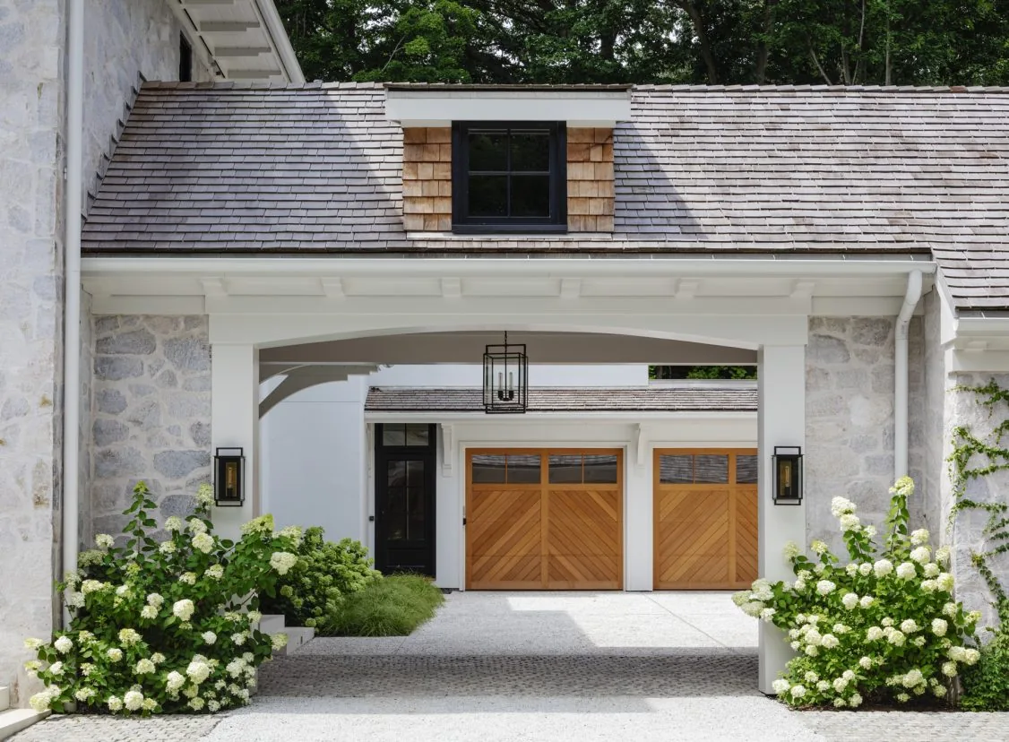 Covered breezeway with dormer window and garage doors clad in wood at Birchwood Terrace