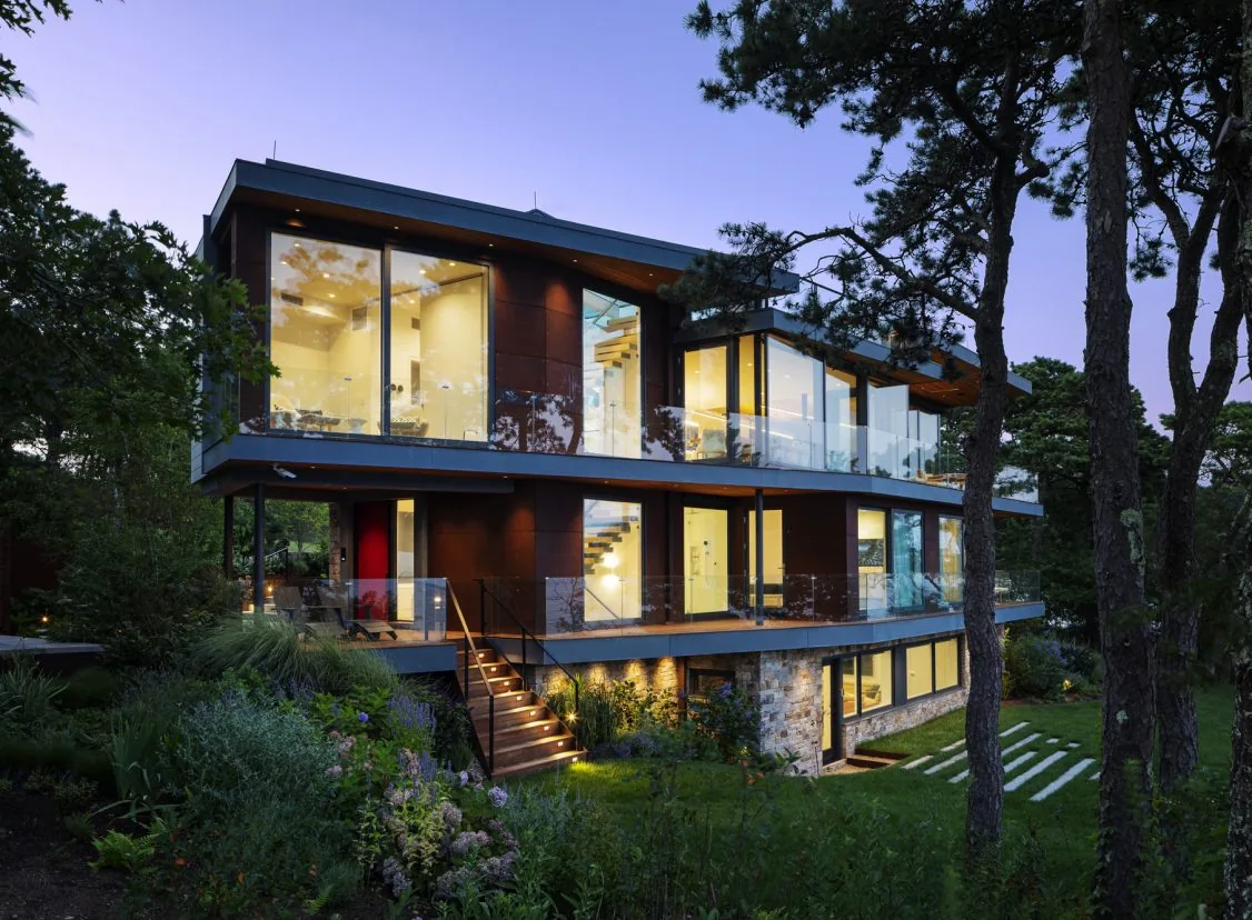 Miter Point is a modern three-story residence featuring extensive floor-to-ceiling glazing and glass balconies.