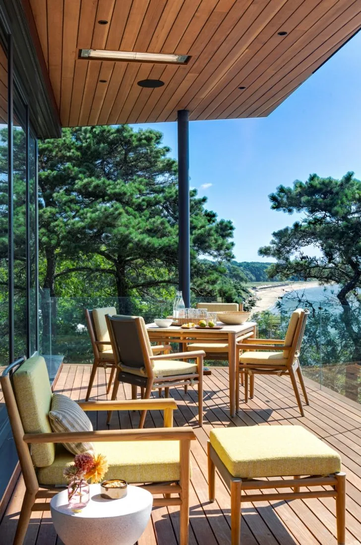Miter Point outdoor living deck with wooden furniture and glass railing overlooking a water view.
