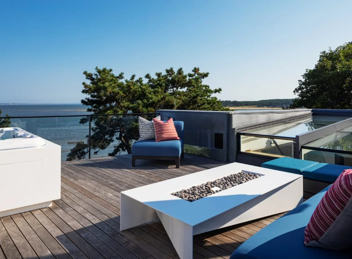 The rooftop deck at Miter Point features modern seating, a linear fire pit, and a glass balcony railing with water views.