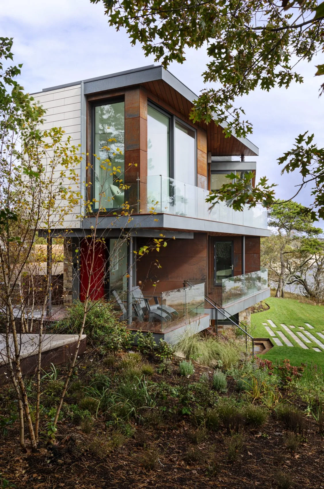 Miter Point features horizontal siding, a stone base, and glass balcony railings with wood ceiling soffits.