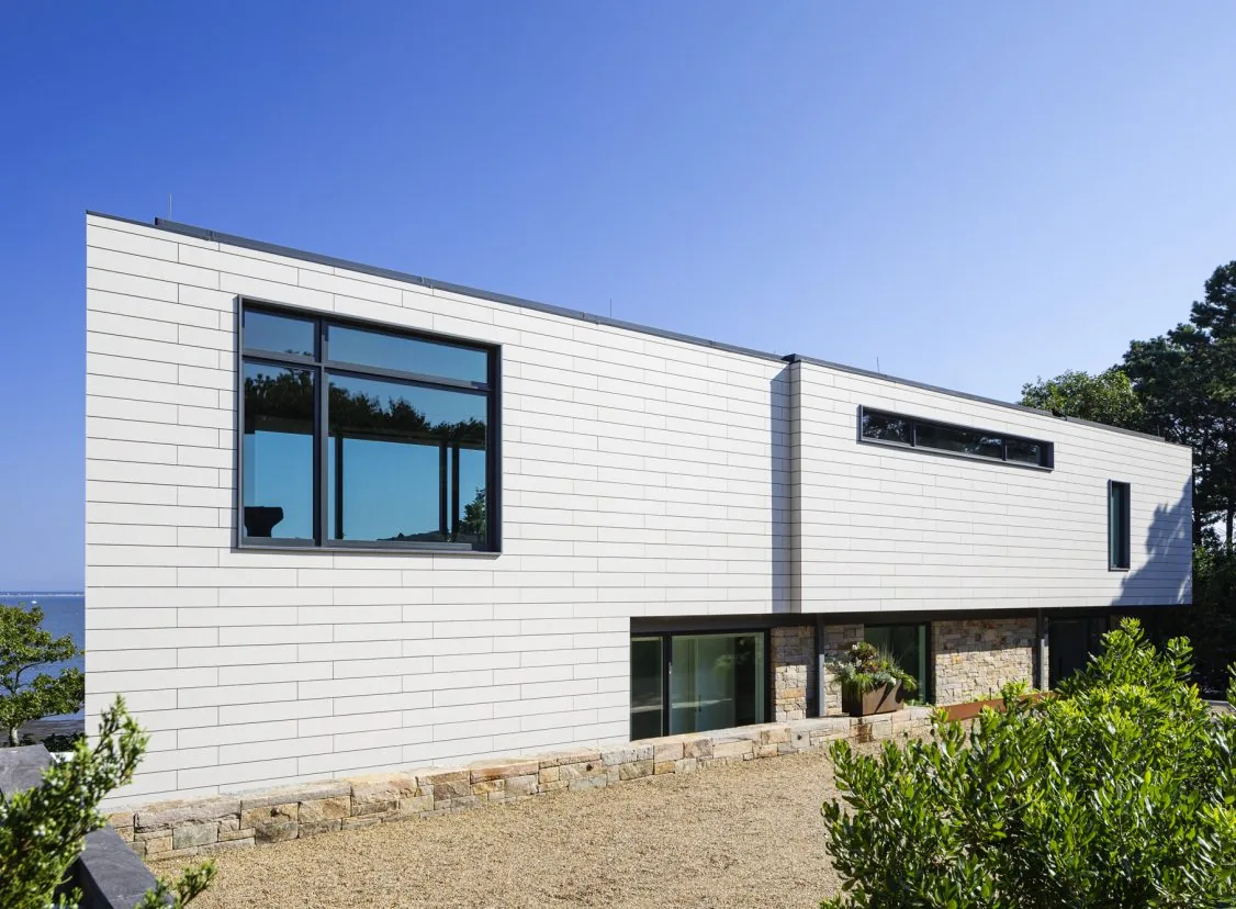 Miter Point project showcasing white horizontal siding with stone base and multiple window styles.