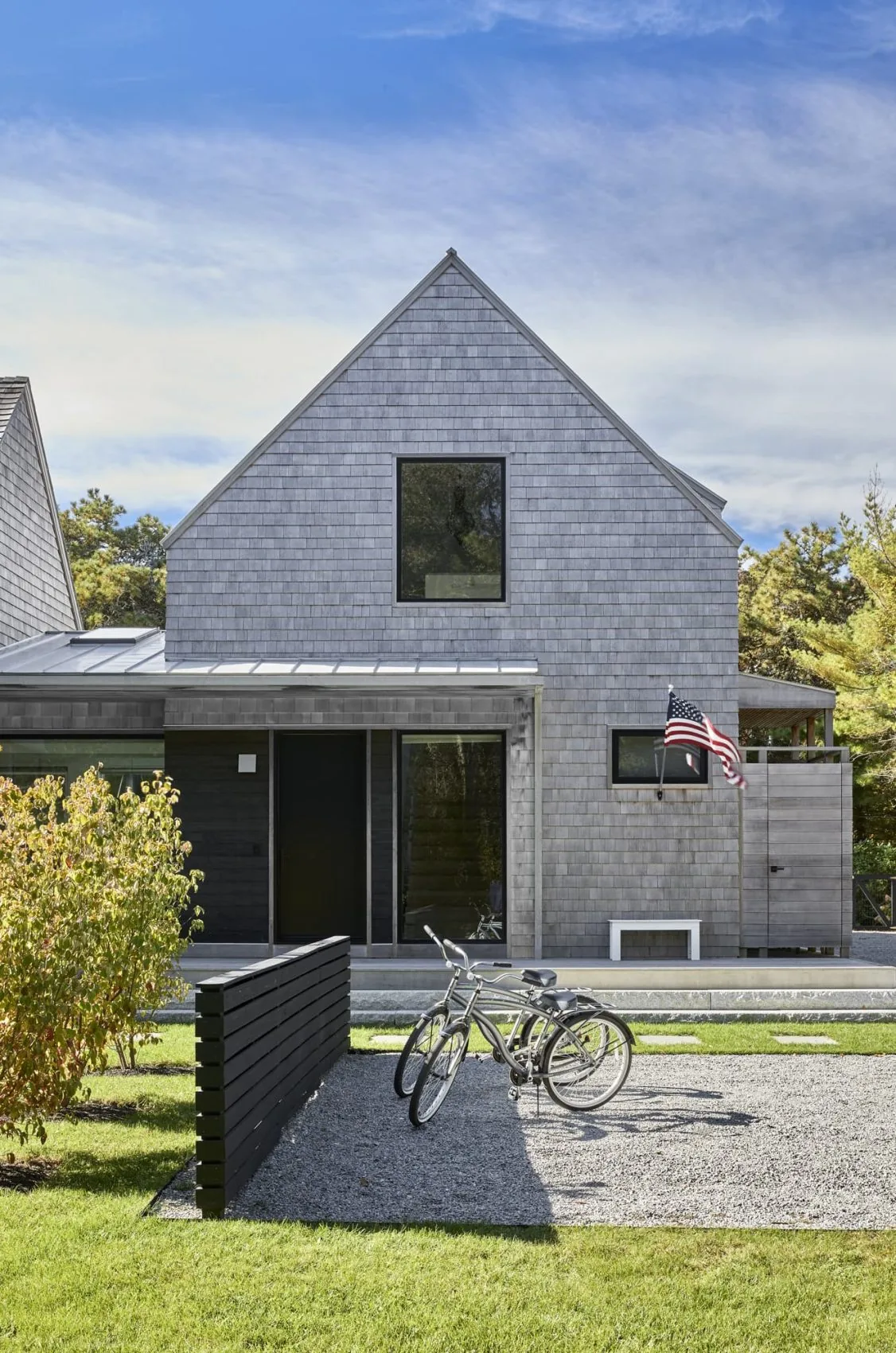 Katama Cove features a gray shingle-clad home with a steep gable roof and outdoor bicycle parking area.