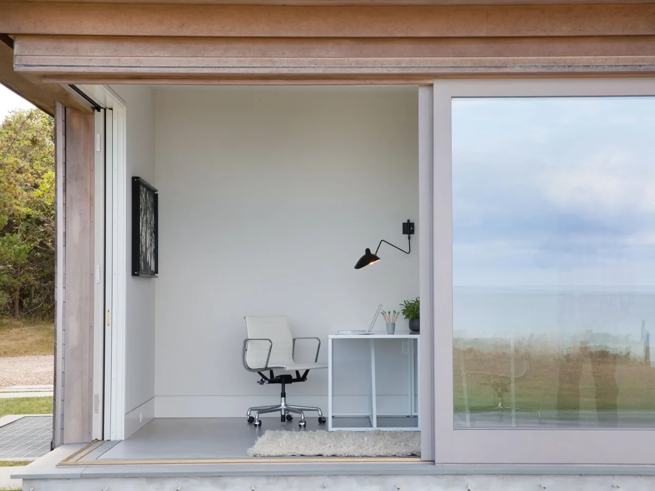 Minimalist home office inside the Island House with ocean views through large glass doors.