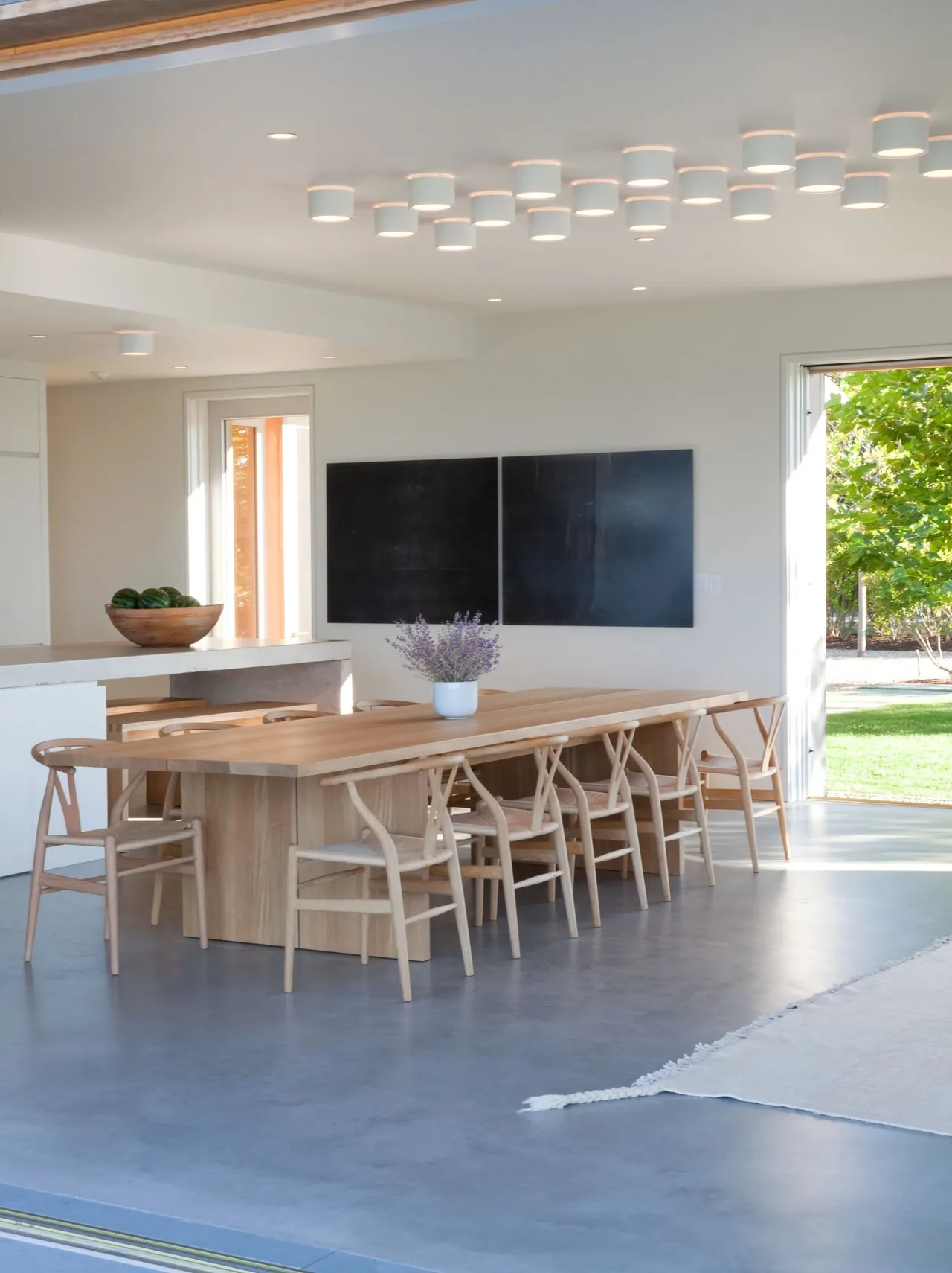 Dining room of Island House with natural wood furniture, minimalist ceiling lights, and indoor-outdoor flow.