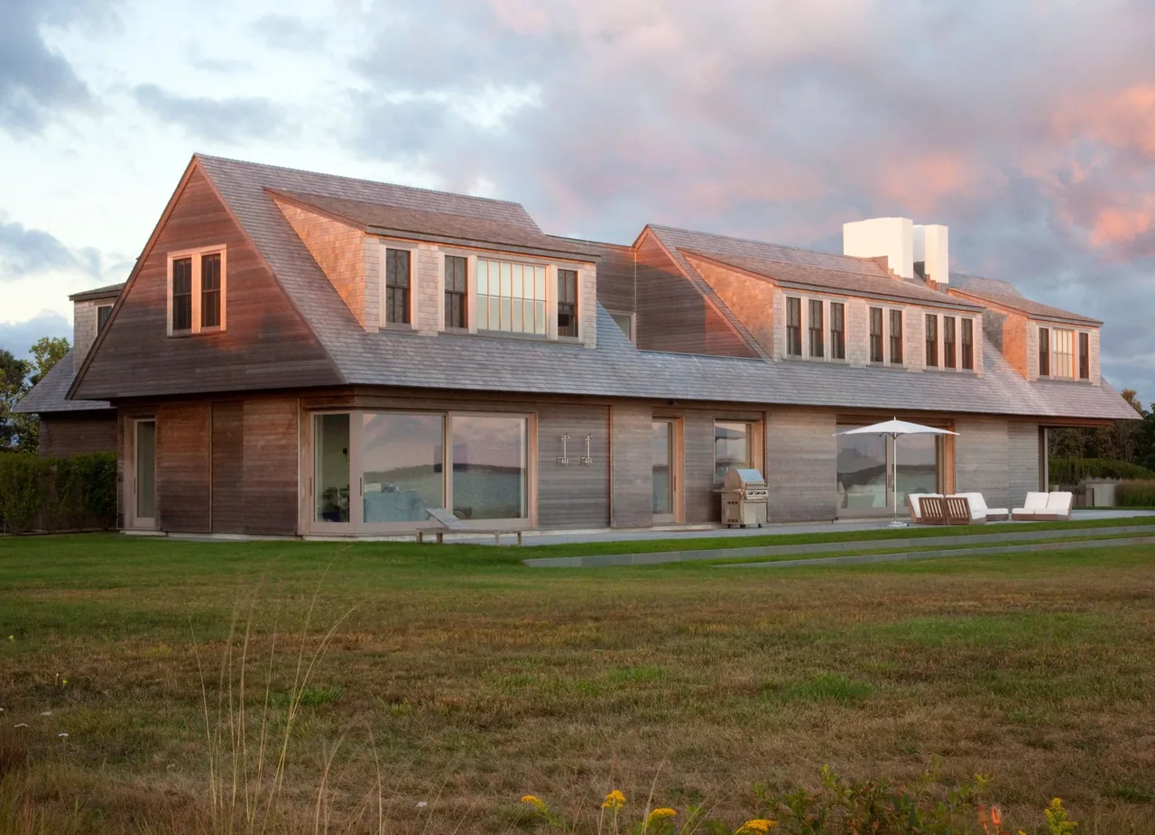 Island House in Boston by Noury-Ello Architects features wooden shingle cladding and large windows overlooking an open lawn.