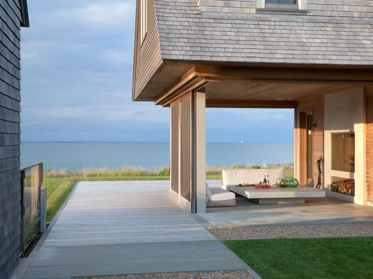 Covered patio space with seating and a fireplace overlooking an ocean view at the Island House.