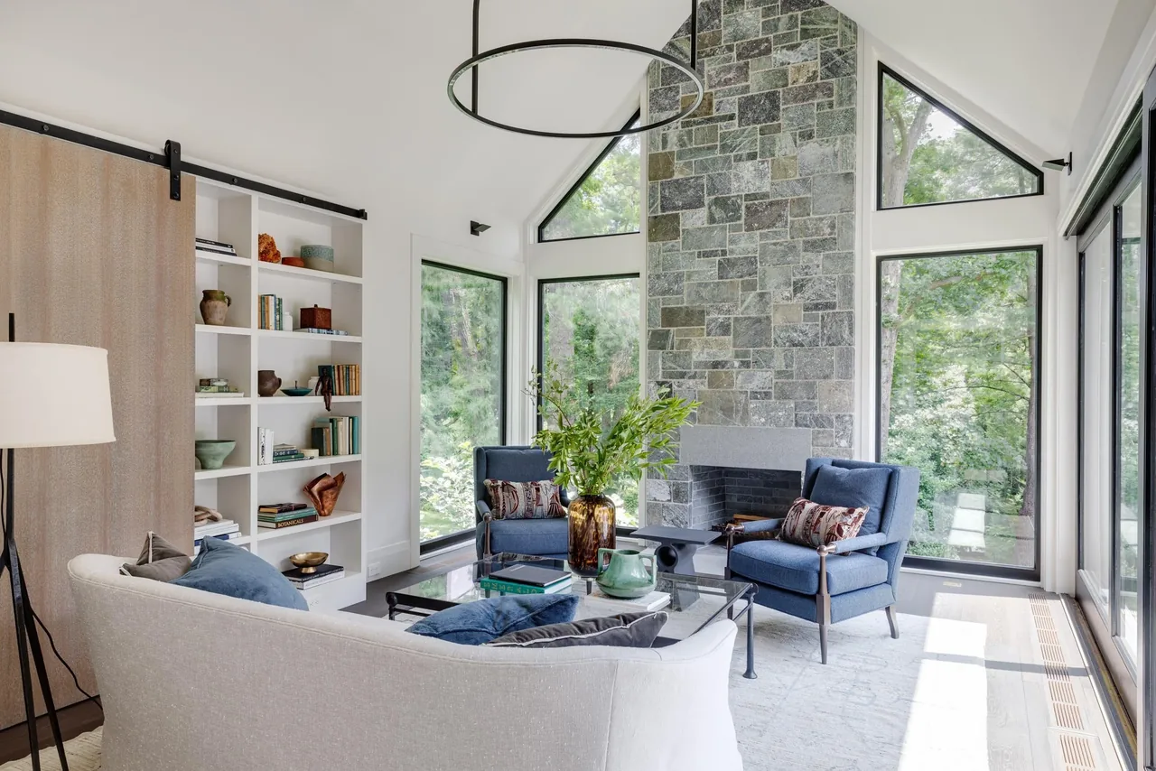 Living room in the Carriage House features a stone fireplace and large triangular windows bringing in natural light.