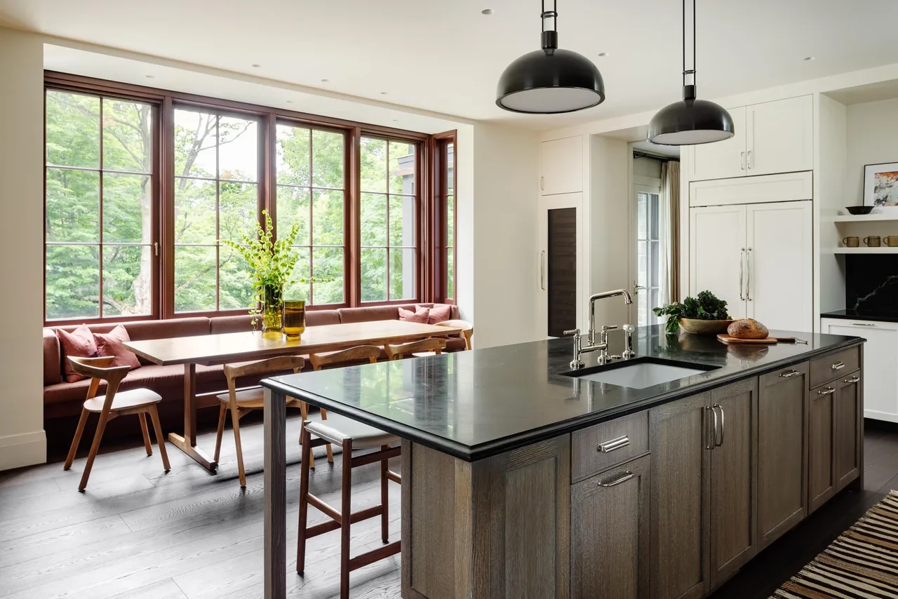 Kitchen featuring a large island with sink and built-in bench seating by tall windows with divided lites.