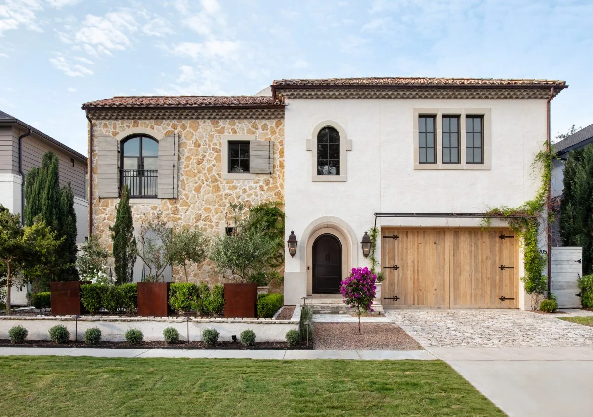 The Old-World French Estate shows a stone and stucco exterior with arched doorways and wood garage doors.