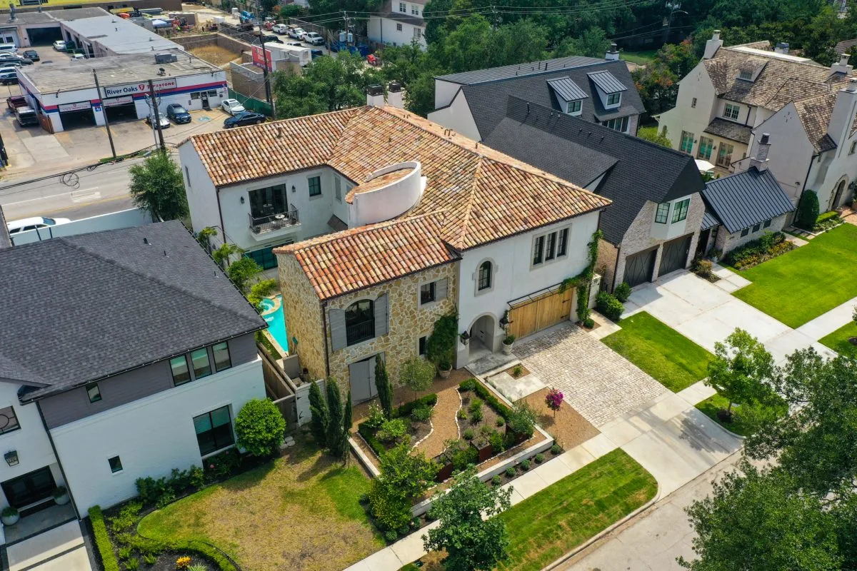 The Old-World French estate features arched doorways, shuttered windows, and a cobblestone driveway.